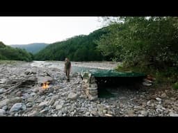 Building of a shelter made of stone near a mountain river, steak fried on fire